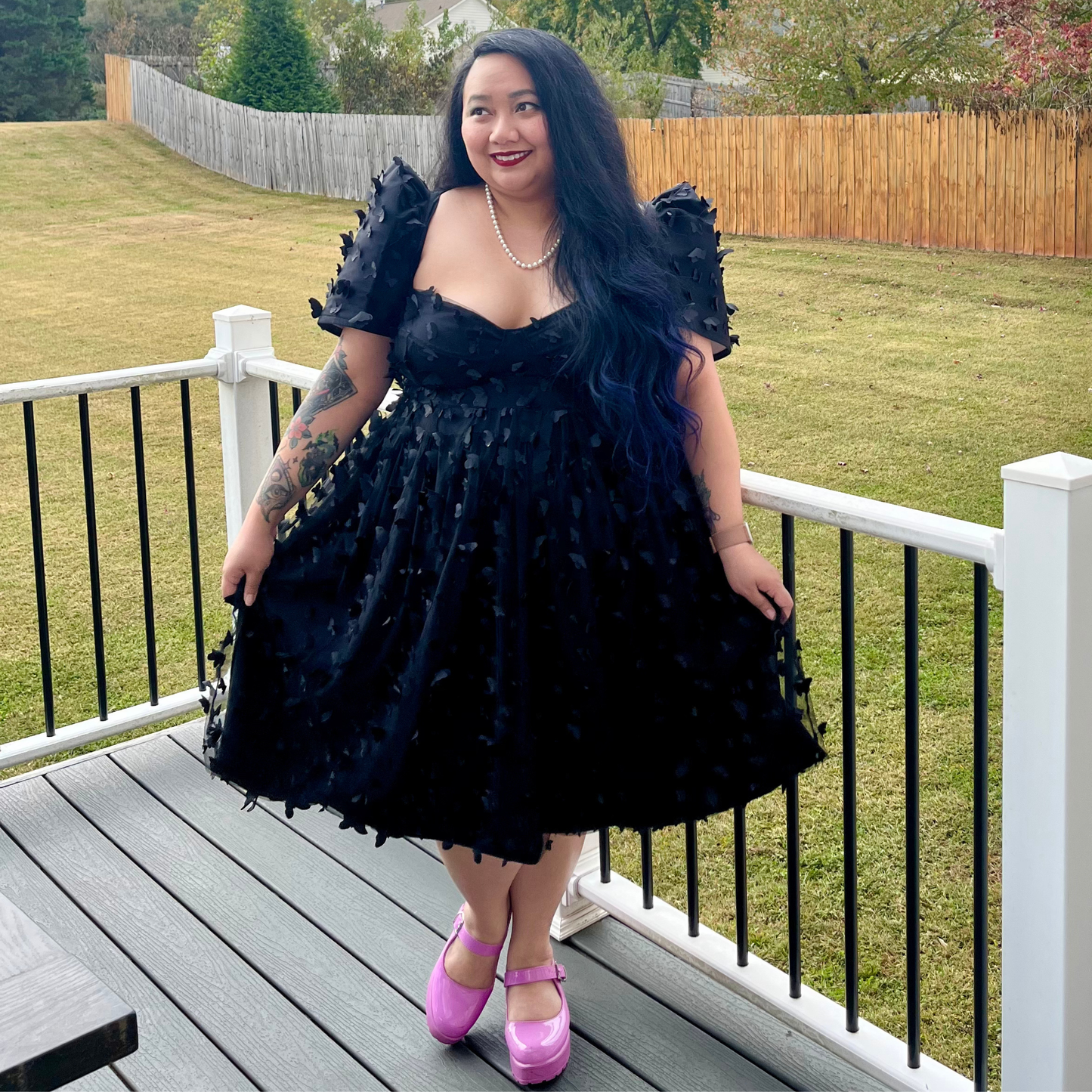 Woman in a black dress standing on a deck.