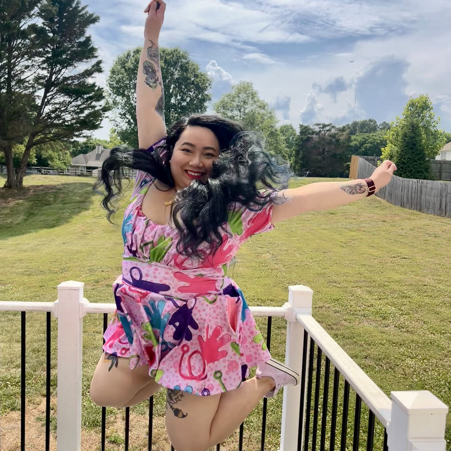 Person in a colorful dress dancing outdoors with trees and grass in the background