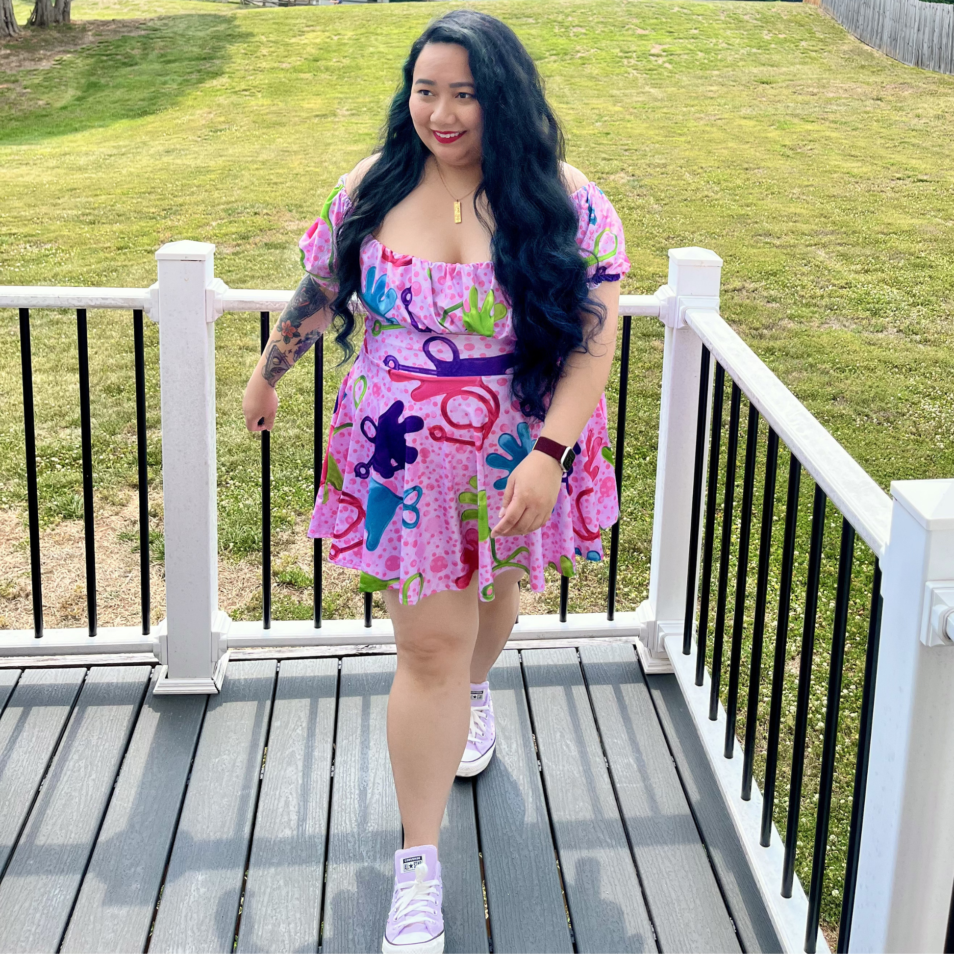 Woman in a colorful dress standing on a deck with grass in the background