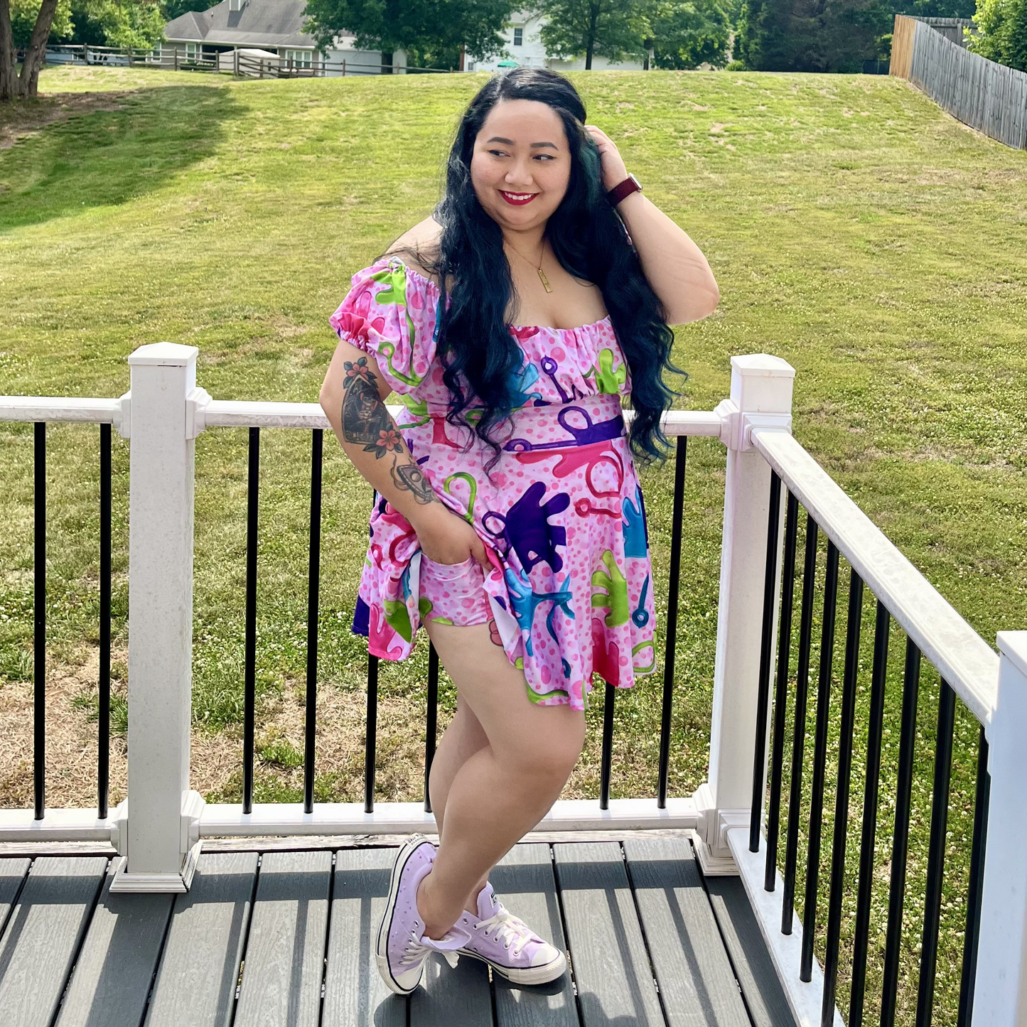 Woman in a colorful dress standing on a deck with grass and trees in the background
