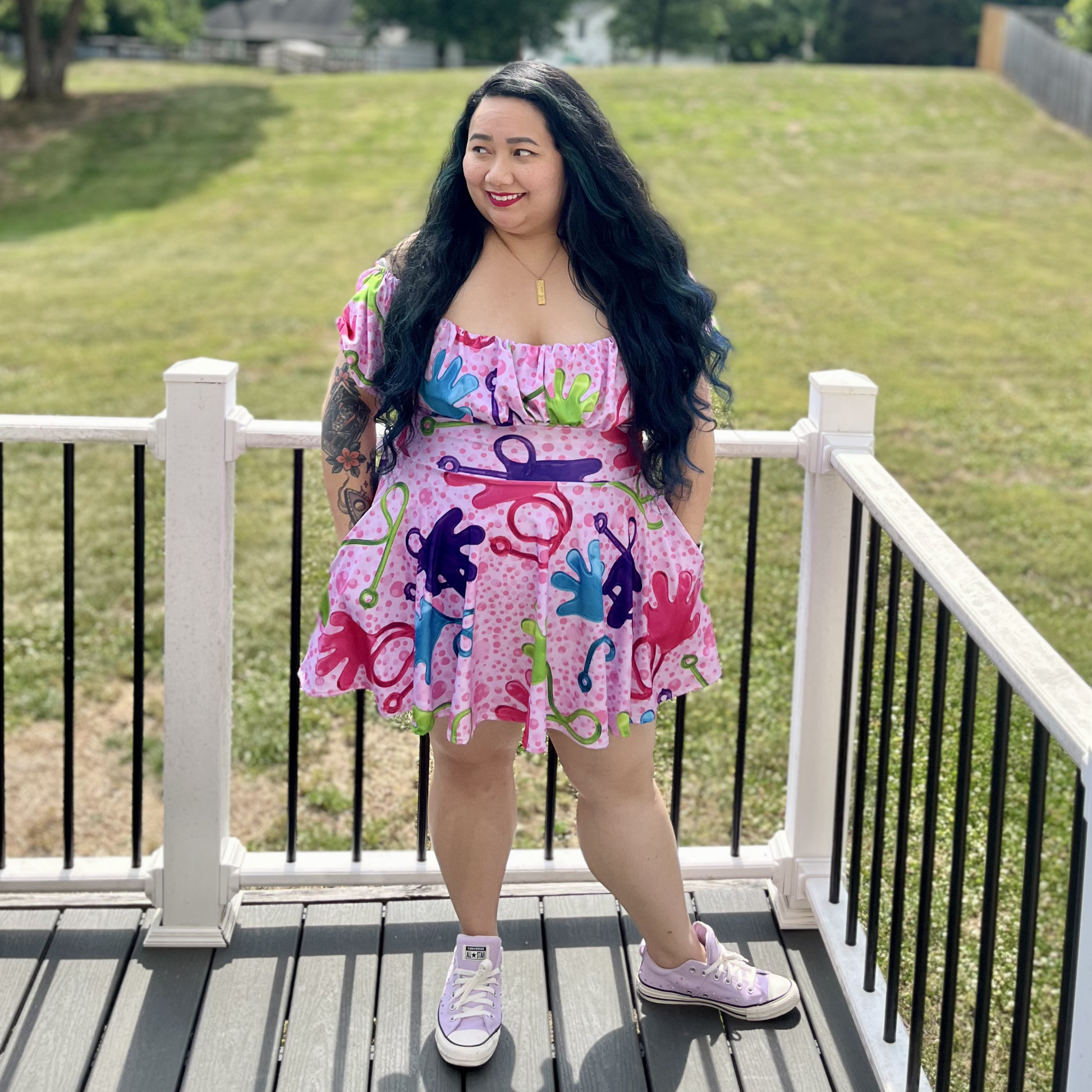 Woman wearing a colorful dress with abstract designs on a wooden deck.
