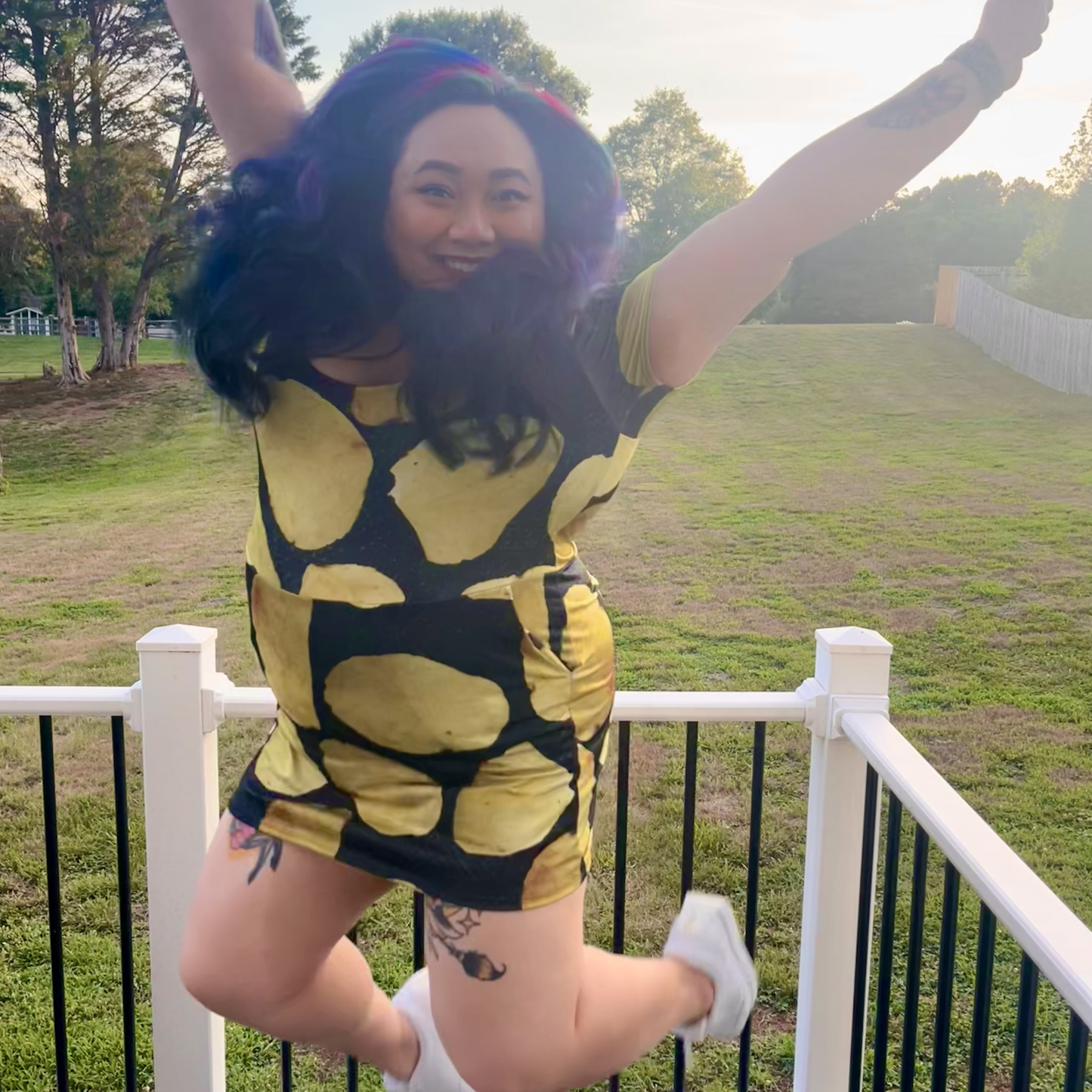 woman jumping on a deck in front of a lawn wearing a potato chip print dress