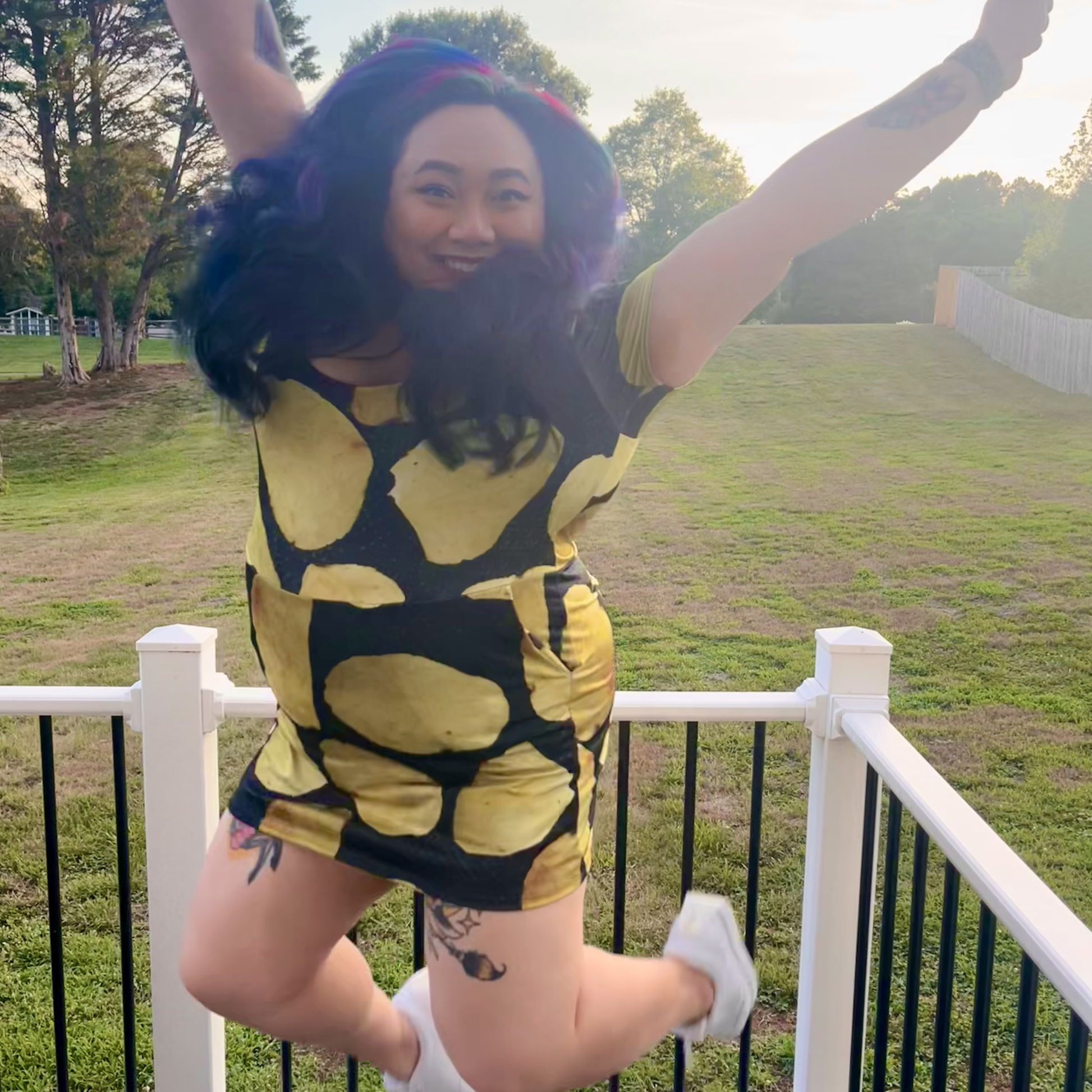 woman jumping on a deck in front of a lawn wearing a potato chip print dress