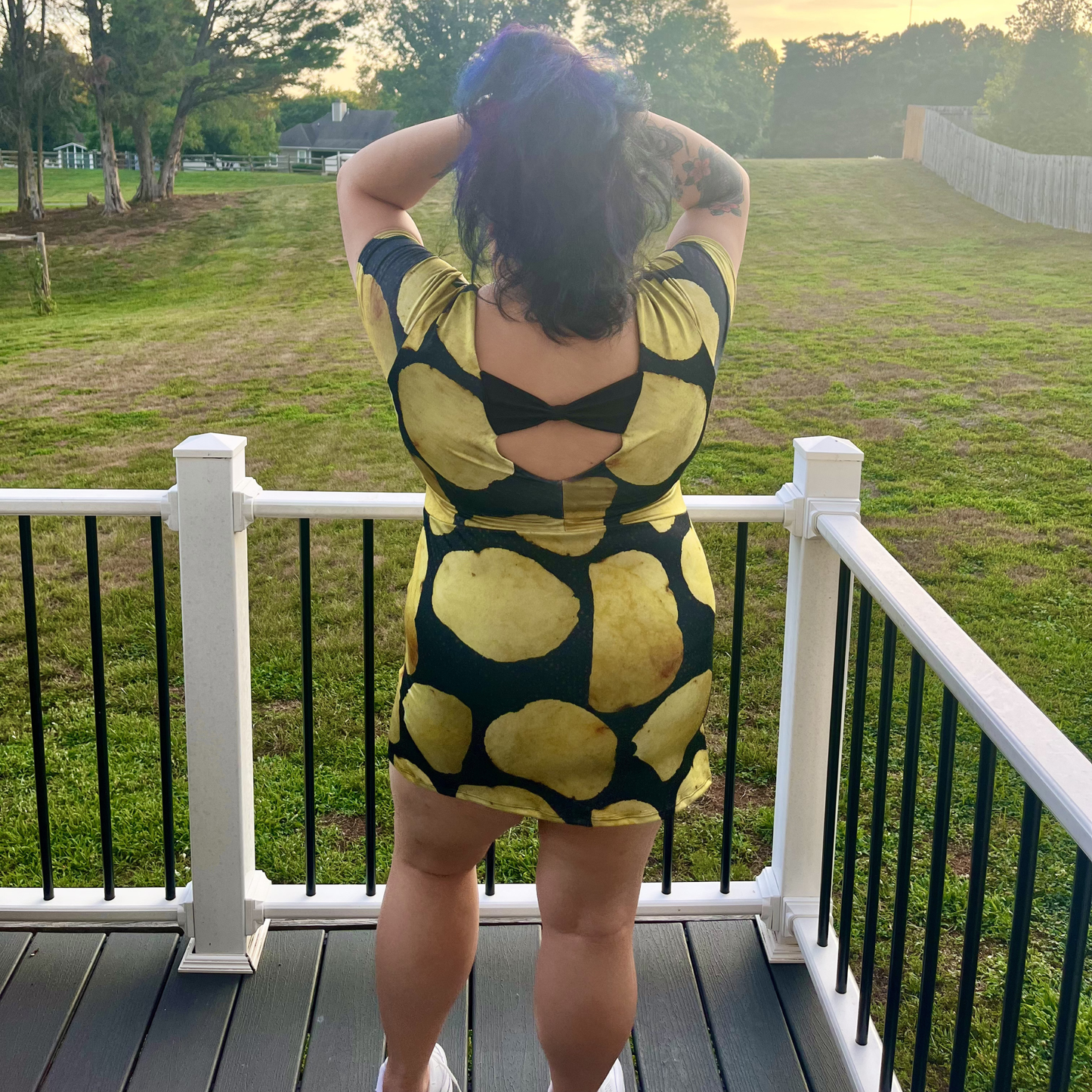 woman standing on a deck in front of a lawn wearing a potato chip print dress
