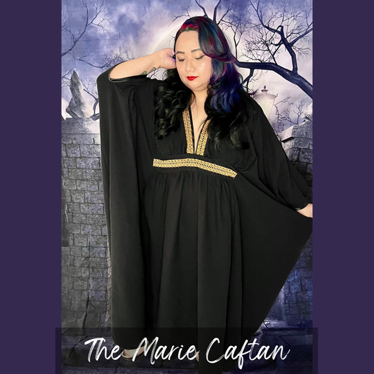 A woman modeling a black caftan with gold trim details, set against a gothic castle background. The text 'The Marie Caftan' is displayed at the bottom.