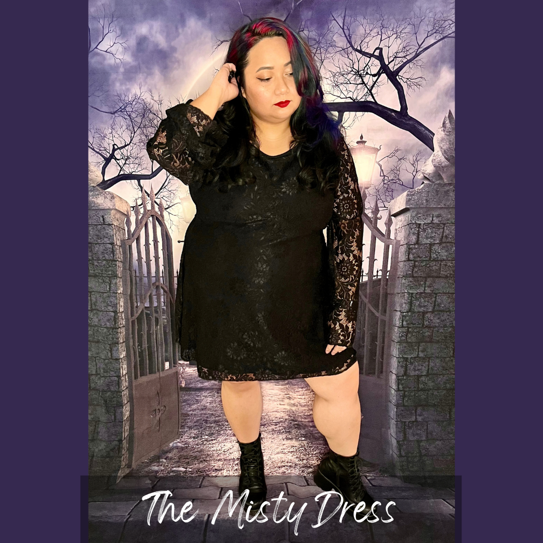 Woman in a black lace long sleeve dress posing in front of a gate