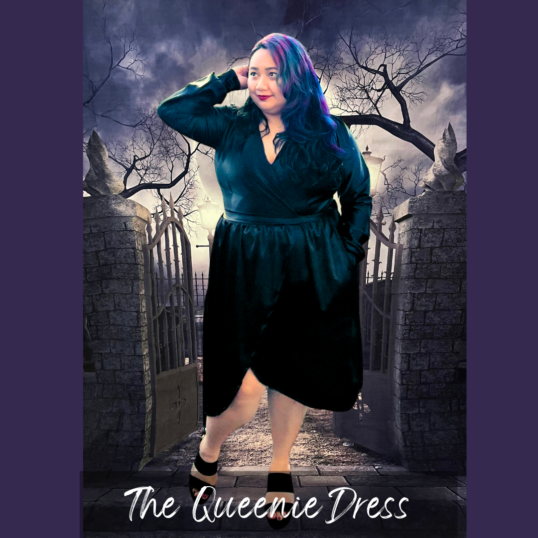 A woman modeling a black wrap-style dress in a gothic cemetery setting with stone gates and bare trees. The dress has long sleeves, a V-neckline, and a gathered waist.