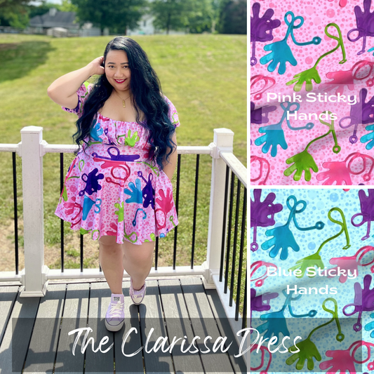 Woman wearing a colorful dress with 'Pink Sticky Hands' design, standing on a deck.