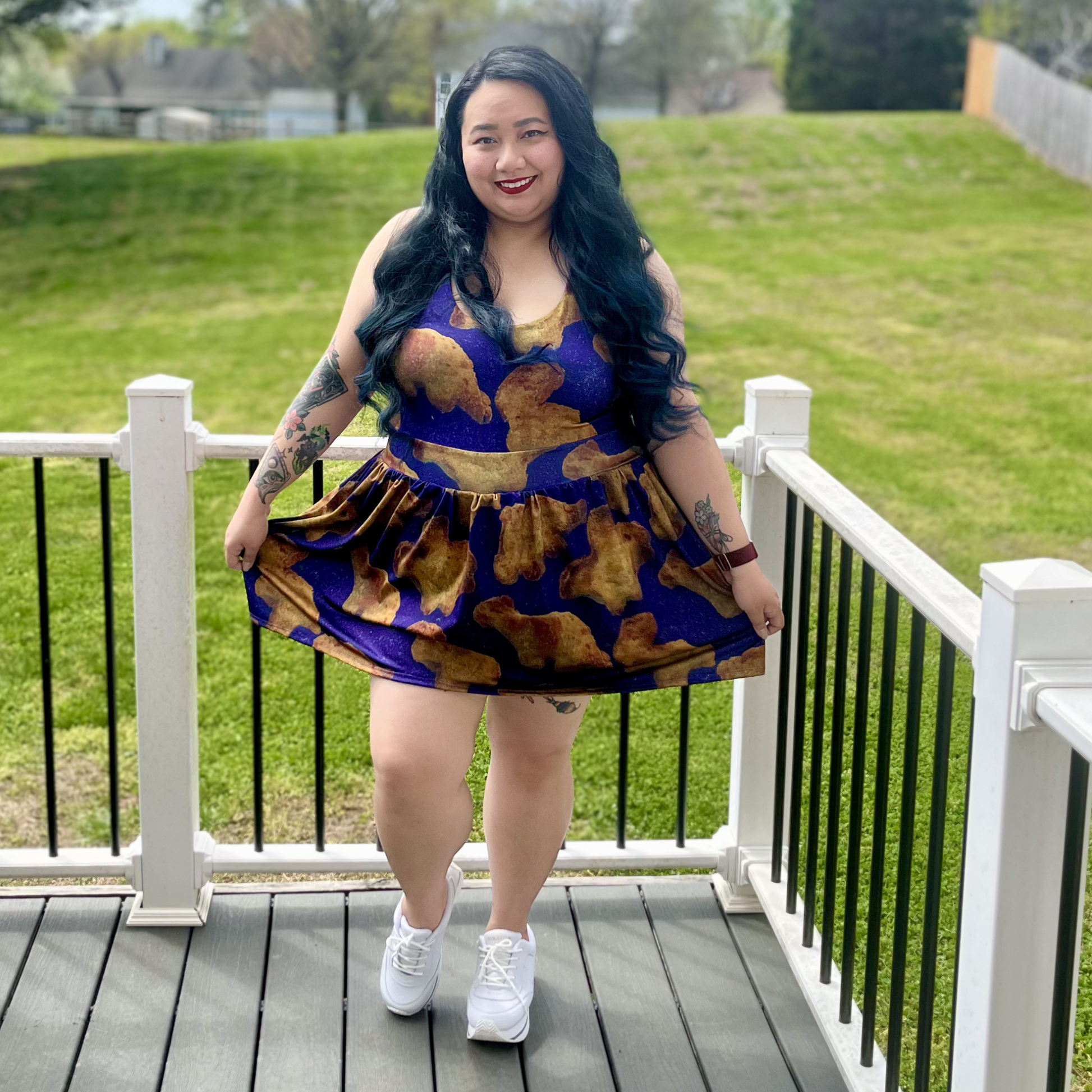 Woman in a purple dress with Dino nuggies print standing on a deck