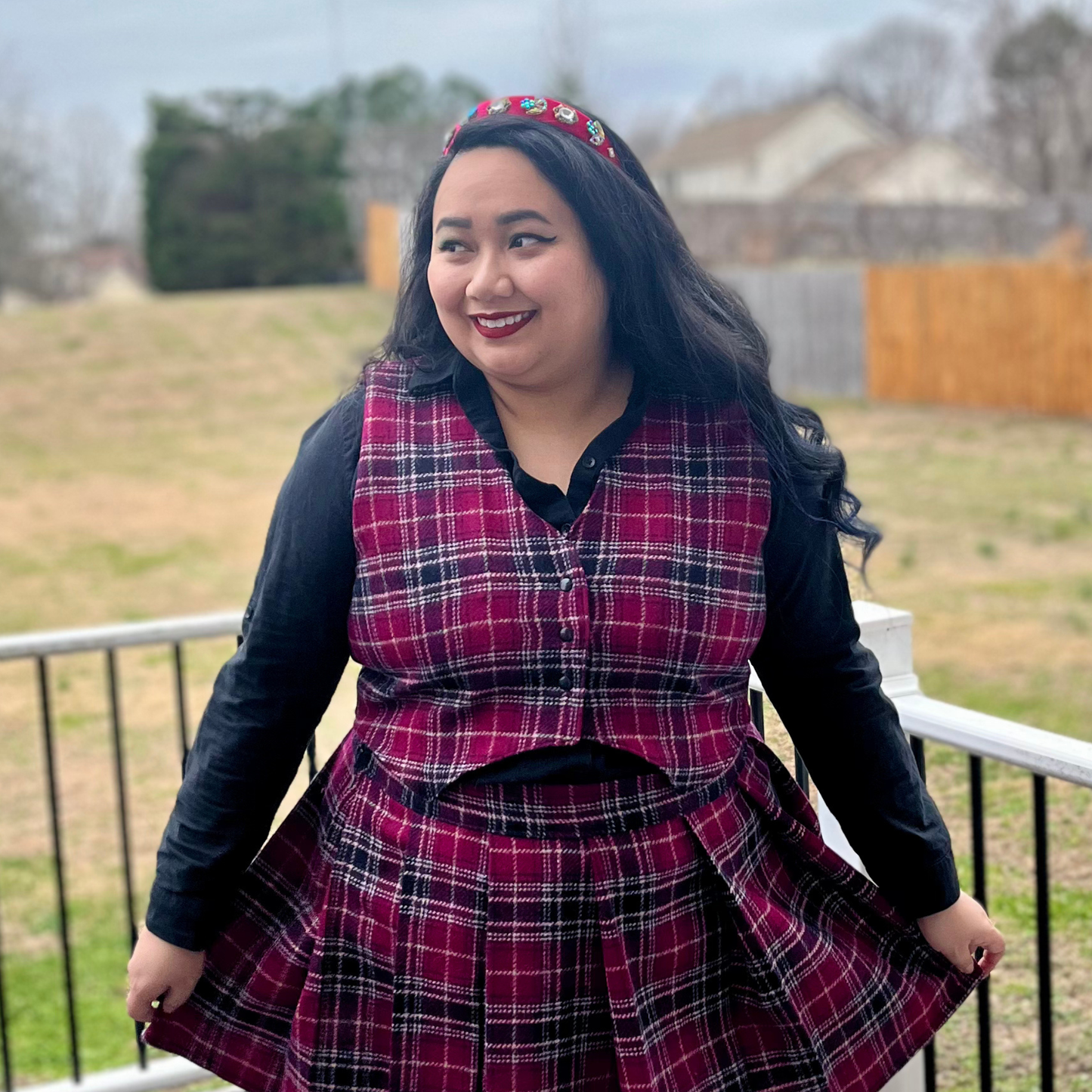 Woman wearing a pink plaid outfit with a black top outdoors.