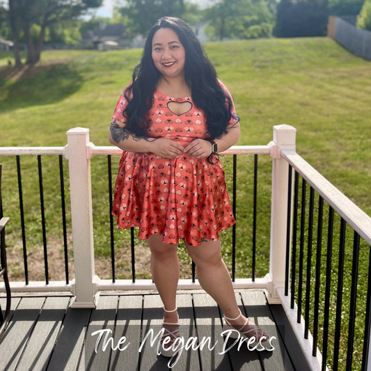 woman in an orange printed dress standing on a deck in front of grass and trees