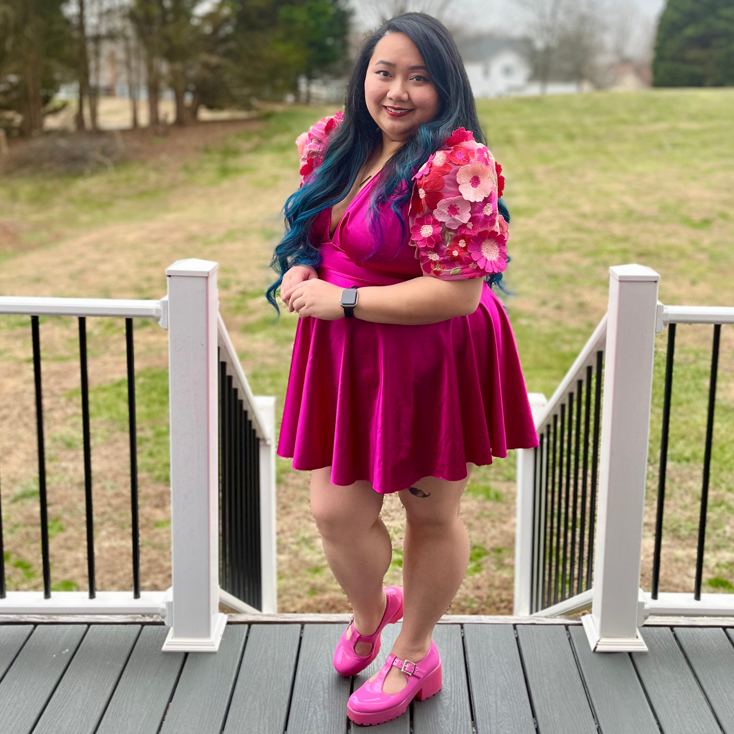 Woman wearing a magenta dress standing on a deck