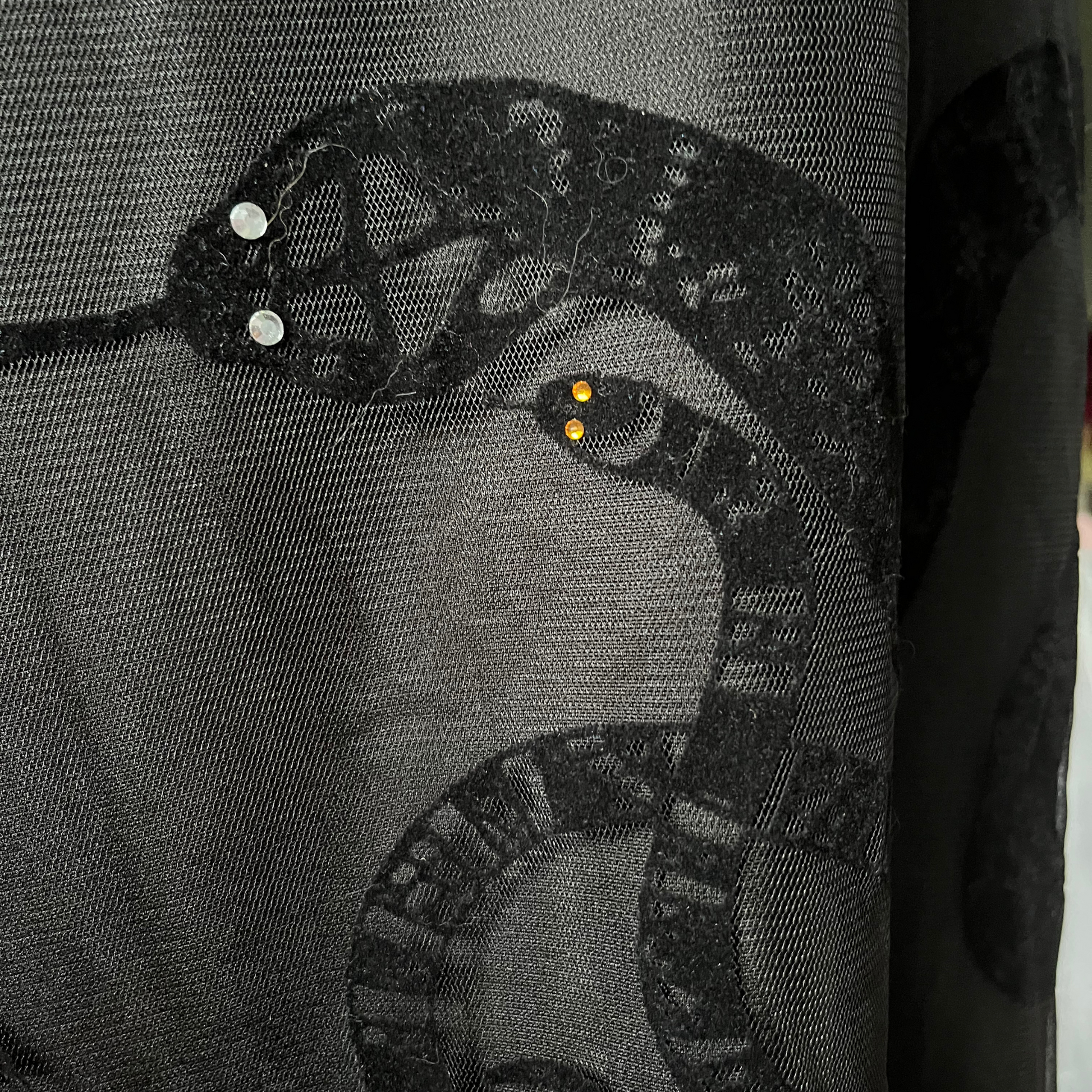 Black flocked snakes on sheer fabric with clear and orange rhinestone eyes
