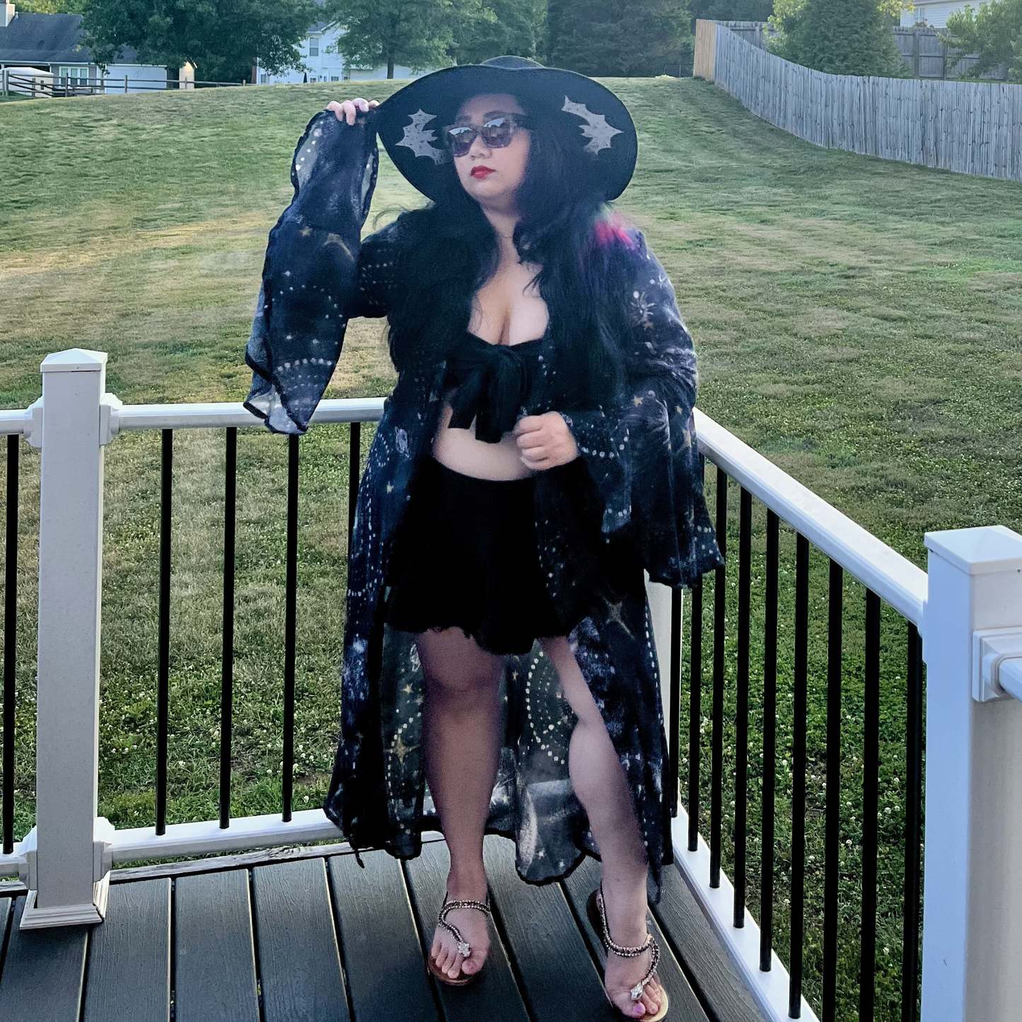 Woman standing on a deck in front of a yard wearing a bikini and a celestial print robe